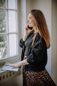 Frau am Fenster, telefonierend