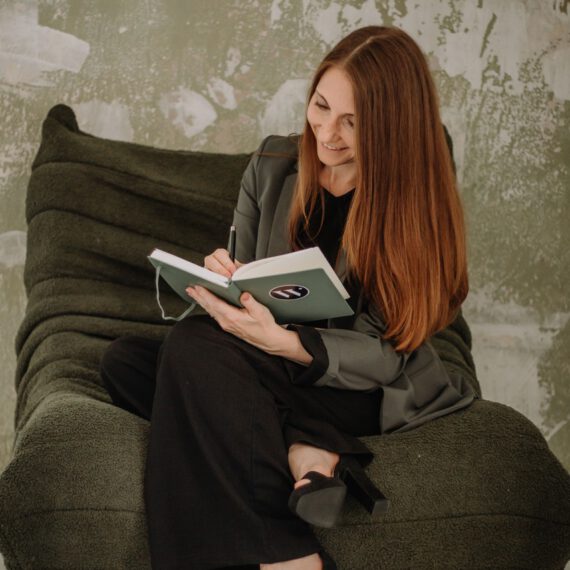 Frau auf grünem Sessel mit Buch in der Hand